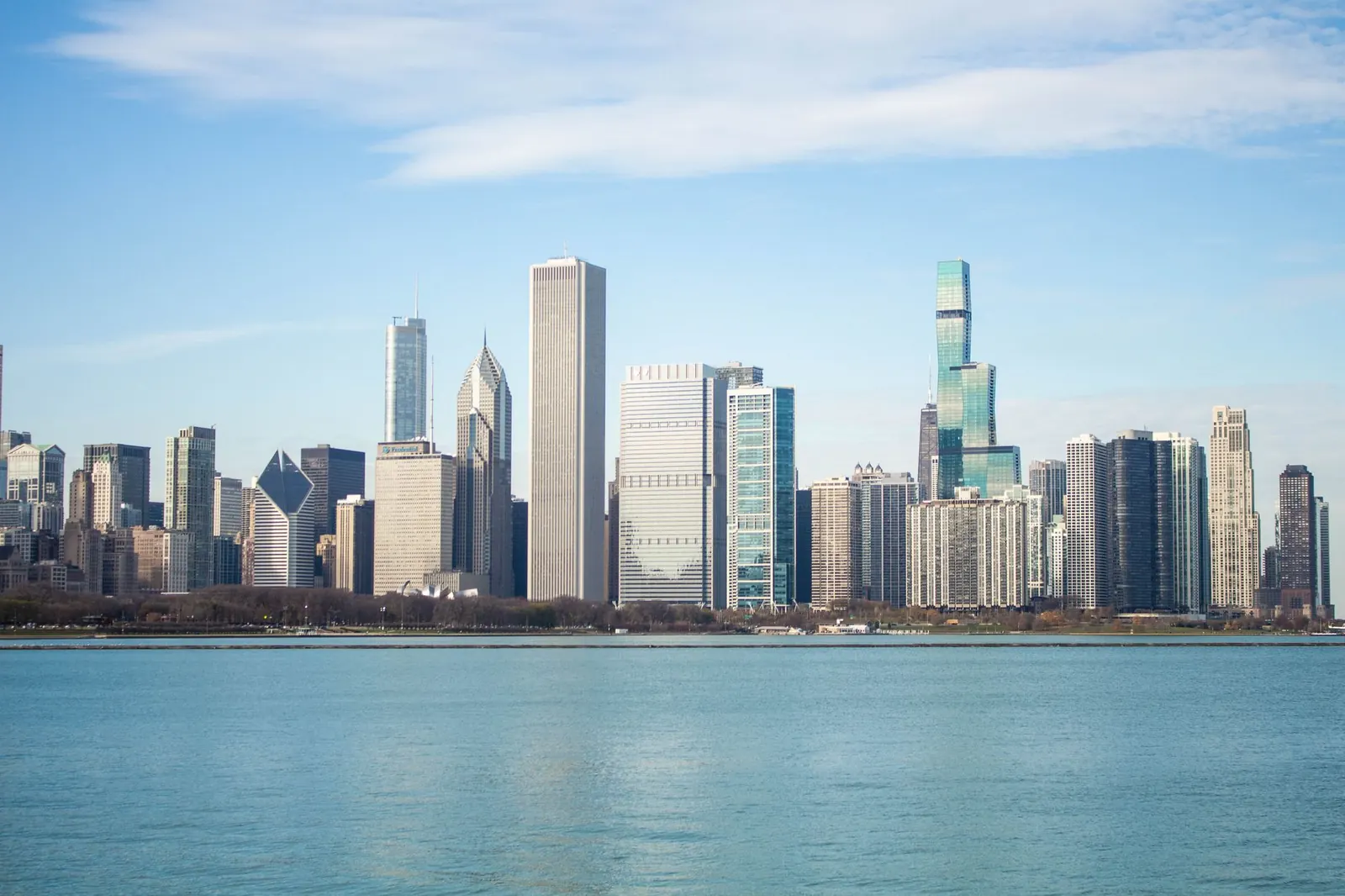 A breathtaking view of the Chicago skyline with iconic skyscrapers by the lake on a sunny day.